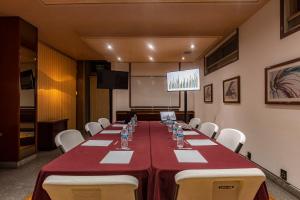 a conference room with a long table with chairs and a screen at Hotel Beverly in Mexico City