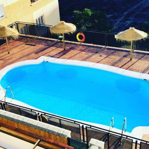 una gran piscina con sombrillas en una terraza en La Casa del Pianista, en Monachil