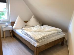 a bed with white sheets and pillows in a room at Zingst Haus Hugo in Zingst