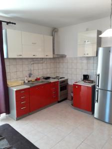 kuchnia z czerwonymi szafkami i lodówką ze stali nierdzewnej w obiekcie Apartments Alen Pula w Puli