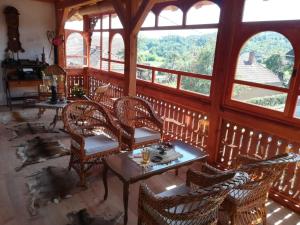 a room with a table and chairs and windows at Country house Todor in Kragujevac