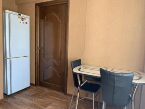 アンガルスクにあるАпартаменты "LUX" в центреのキッチン(テーブル、椅子2脚、冷蔵庫付)
