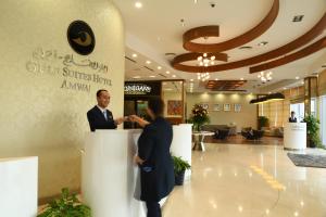 een man en een vrouw die aan een balie in een lobby staan bij Gulf Suites Hotel Amwaj in Manamah