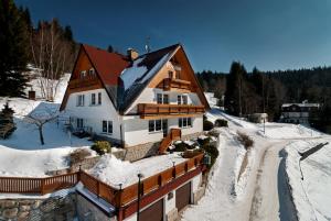 ein Haus im Schnee auf einer verschneiten Straße in der Unterkunft Pension Fuka in Špindlerův Mlýn