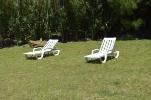 two white chairs sitting in a field of grass at Quinta dos Mangues in São Martinho do Porto