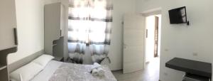 a white bedroom with a bed and a television at Le Cale in Lampedusa