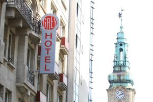un panneau sur le côté d'un bâtiment avec une tour d'horloge dans l'établissement Hotel Grey, à Luxembourg