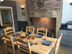 mesa de madera con sillas y chimenea en Last Cottage en Newbiggin-by-the-Sea