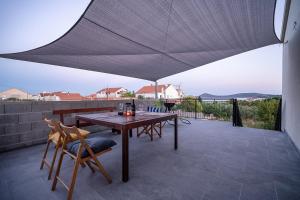 une table et des chaises en bois sur une terrasse avec un parasol dans l'établissement Apartman Vodice, à Vodice