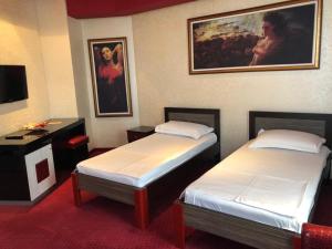 um quarto de hotel com duas camas e um quadro na parede em Grand Hotel Petrol em Fier