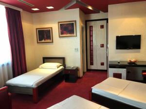 a hotel room with two beds and a flat screen tv at Grand Hotel Petrol in Fier