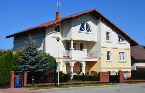 a white and yellow house with a fence at Aven'a pokoje gościnne z basenem in Darłowo