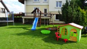 a playground with a slide and a play house at Aven'a pokoje gościnne z basenem in Darłowo