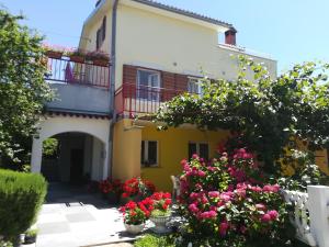 una casa amarilla con flores delante en Apartments Sara en Labin