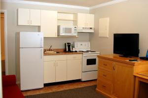 a kitchen with white cabinets and a white refrigerator at Ramada by Wyndham Duncan Cowichan Valley in Duncan