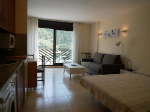 een kamer met een bed en een woonkamer met een bank bij Genciana-Vacances Pirinenca in El Tarter
