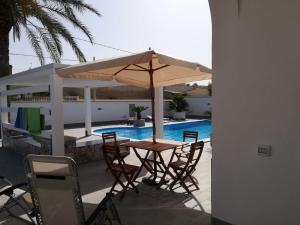 a table with an umbrella next to a swimming pool at Donna Concetta in Mazara del Vallo