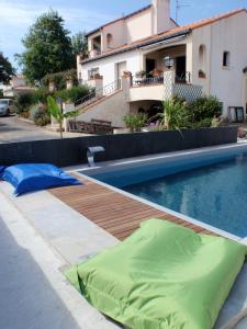 una piscina con una balsa verde junto a una casa en La Belgerie en La Bernerie-en-Retz