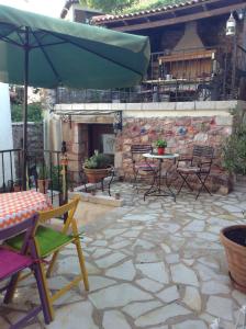 a patio with a table and chairs and an umbrella at Proselinos in Dimitsana