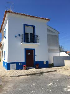 a white house with a door and a balcony at Casa Azul in Almograve