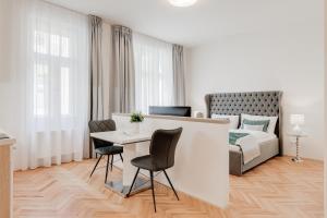 een witte kamer met een bed en een tafel en stoelen bij Gold Art Apartments in Praag