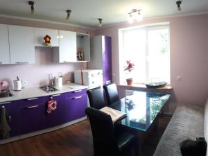 a kitchen with purple cabinets and a table and a window at Apartment by the sea (5 minute walk) in Tūja