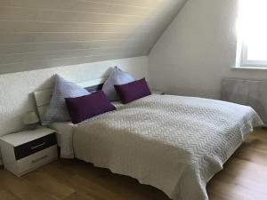 a bedroom with a white bed with purple pillows at Ferienwohnung Elina in Maxhütte-Haidhof