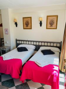 two beds in a room with red sheets at Pensión Aduar in Marbella