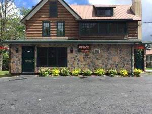 una casa con un edificio de piedra con garaje en Pine Knoll Hotel Lakeside Lodge & Cabin en Old Forge