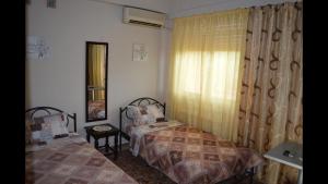 1 dormitorio con 2 camas y ventana en Anita's hosting, en Kalamata