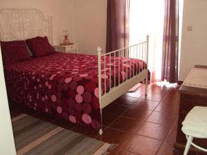 a bedroom with a bed with a red comforter at O Miradouro in Fonte Longa