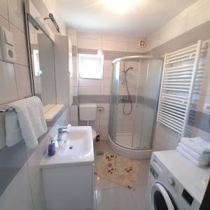uma casa de banho branca com um chuveiro e um lavatório. em Amazing View em Podstrana