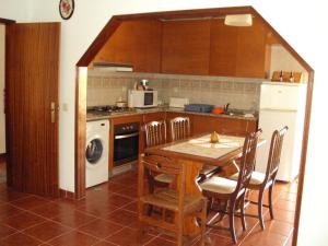 a kitchen with a table and a stove and a refrigerator at O Miradouro in Fonte Longa
