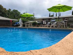 uma piscina com dois guarda-sóis e cadeiras verdes em Red Bluff Inn em Red Bluff