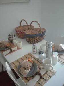 a table with plates and cups and baskets on it at Palm Guesthouse B&B Rooms in Cascais