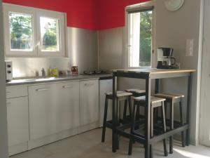 a kitchen with white cabinets and a counter with stools at Le petit pays in Montgivray