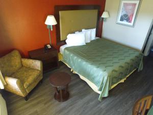 um quarto de hotel com uma cama e uma cadeira em Cross Road Motel em Trenton
