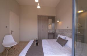 a bedroom with a bed with a chair and a window at Vivari Acta in Vivari