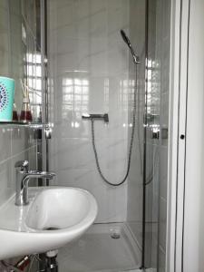 a white bathroom with a shower and a sink at Villa Sunshine in Bagneux