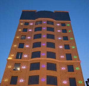 a tall building with christmas lights on it at Durrat Manzli ApartHotel in Al Khobar