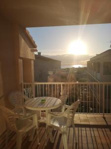 a table and chairs on a balcony with the sunset at Marina 1 in Es Pujols