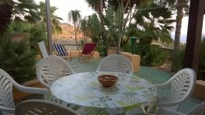 a table and chairs on a patio with palm trees at L'Oasi di Recale in Scauri