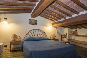 a bedroom with a blue bed and wooden ceilings at Borgo Buio Town House in Montepulciano