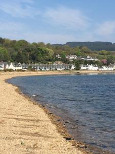 a view of a beach with houses in the background at 1 Shiphouse Apartment in Lamlash