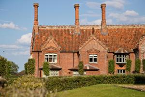 a large brick building with two chimneys on it at Victoria in Holkham