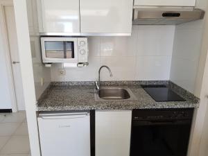 a kitchen with a sink and a microwave at Apartamentos Maria Victoria in Benidorm