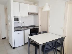 a kitchen with a table and a refrigerator at Apartamentos Maria Victoria in Benidorm