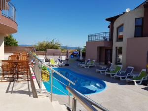 a swimming pool with a slide and chairs and a house at Sea & Hill Guest Houses хотелски тип in Lozenets