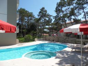 a swimming pool with an umbrella and a patio at Residence Melograno in Bibione