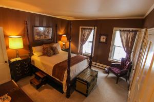 a bedroom with a large bed and a chair at Admiral Peary Inn in Fryeburg